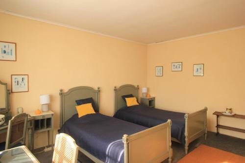2 łóżka w pokoju z żółtymi ścianami w obiekcie L Ancienne Ferme w mieście Connantre
