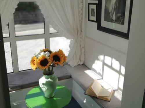 Rosemullion Hotel في فالموث: مزهرية مع عباد الشمس على طاولة أمام النافذة