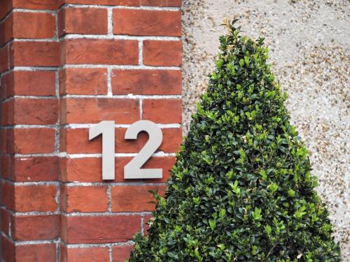 eine Hausnummer an einer Backsteinmauer neben einem Weihnachtsbaum in der Unterkunft Saffrons Apartment in Eastbourne
