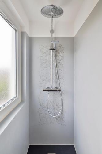 La salle de bains est pourvue d'une douche et d'un mur blanc. dans l'établissement Le MoZen - Appartement proche hippodrome - St Malo, à Saint-Malo