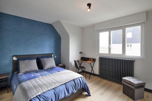une chambre avec un grand lit avec un mur bleu dans l'établissement Le MoZen - Appartement proche hippodrome - St Malo, à Saint-Malo