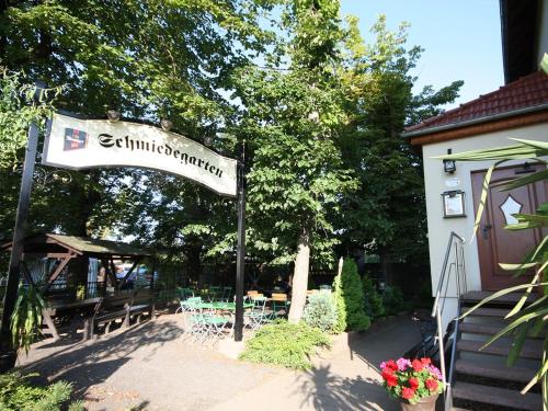 德勒斯登的住宿－Pension Schmiedeschänke，户外餐厅的标志,配有桌椅