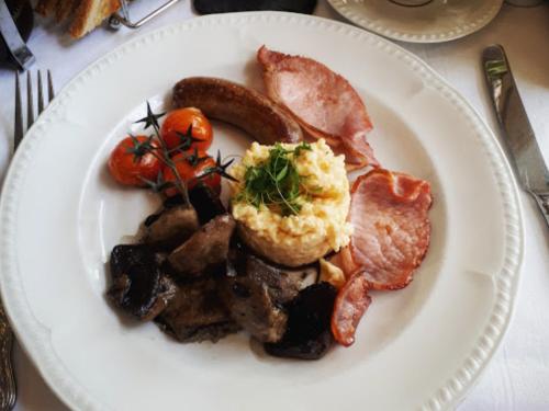 un plato blanco de comida con salchichas de tocino y huevos en Sebastians, en Oswestry