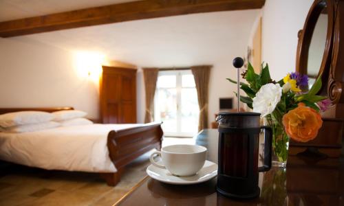 a hotel room with a coffee cup and flowers on a table at Shave Cross Rooms in Bridport