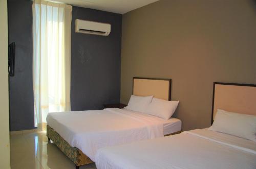Senrose Hotel Kuantan في كُوانتان: غرفة نوم بسريرين وملاءات بيضاء ونافذة
