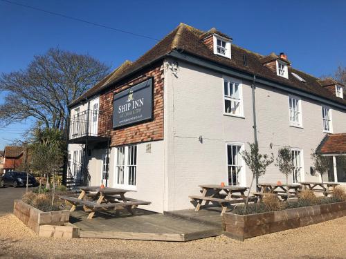 um edifício com mesas de piquenique em frente em The Ship Inn em Dymchurch