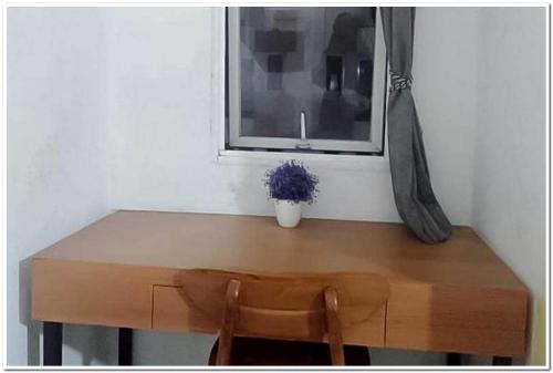 een houten tafel met een potplant en een raam bij RedDoorz Apartment at Grand Sentraland Karawang in Telukjambe