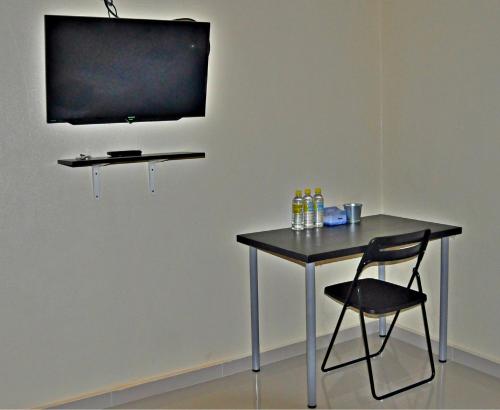 einen Tisch mit einem Stuhl und einen TV an der Wand in der Unterkunft Tanjong Inn in Kota Bharu