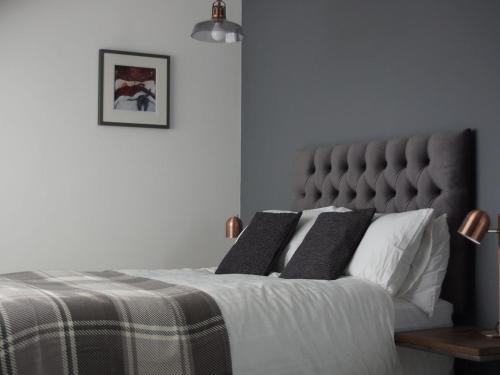 a bedroom with a bed with a gray headboard at Skyline Guesthouse in Newquay