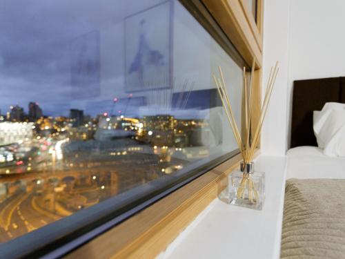 una camera da letto con finestra affacciata sulla città di Live in Leeds Sky Penthouse a Leeds