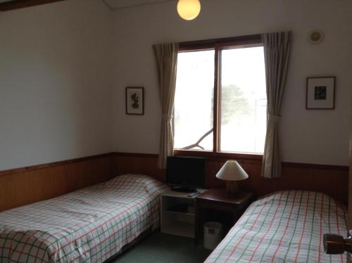輕井澤的住宿－草上飛酒店，配有书桌和窗户的客房内的两张床