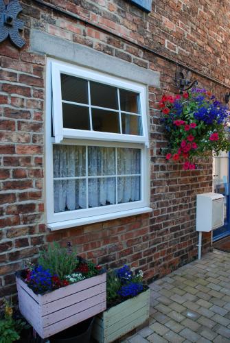a window on a brick wall with flowers and plants at Saltburn Holidays Primrose Cottage in Guisborough