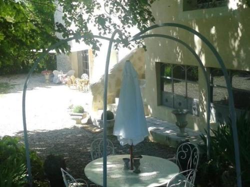 a table with a white umbrella in a yard at Le Moulin de Sonnailles in Cabriès