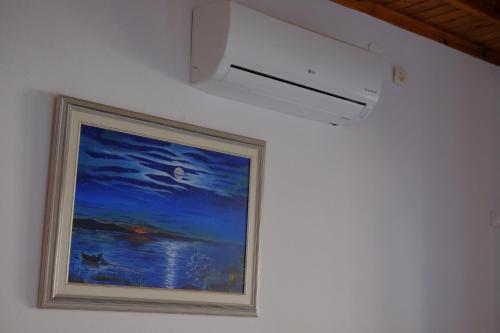 a painting hanging on a wall with a light at Villa Aleka in Samothráki