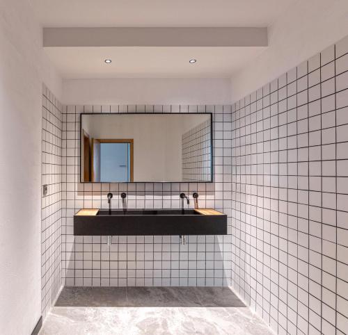 y baño con paredes de azulejos blancos y espejo. en Hotel Forum Ceao en Lugo