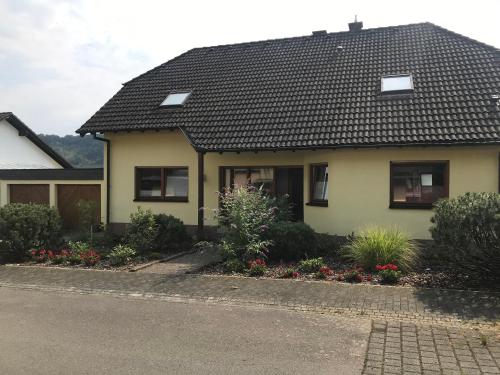 una casa amarilla con techo negro en Moselblick am Waldrand, en Traben-Trarbach