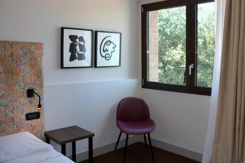 a bedroom with a red chair and a window at Anusca Palace Hotel in Castel San Pietro Terme