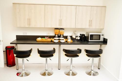 a kitchen with a counter with four bar stools at Serviced Property Plymouth in Plymouth