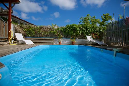 a large blue swimming pool with two chairs in a yard at Holiday Home Soleil de Gwada in Sainte-Anne