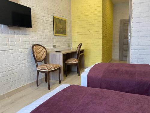 um quarto com duas camas e uma secretária com duas cadeiras em Art хостел-готель "Адреналін" em Lutsʼk