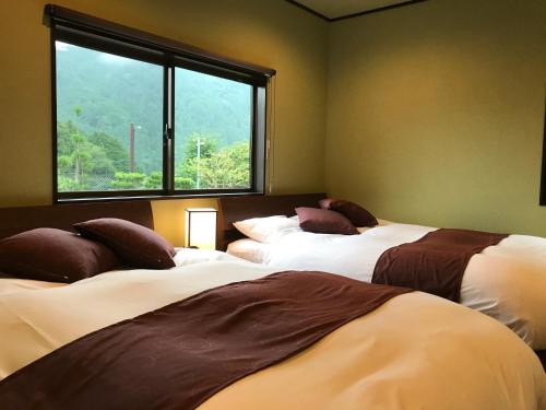 two beds in a room with a window at Ohara Sensui Surrounded by Beautiful Nature in Kyoto