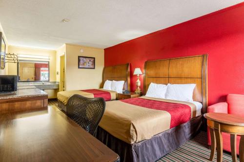 - 2 lits dans une chambre d'hôtel dotée d'un mur rouge dans l'établissement Econo Lodge Charlotte Airport Area, à Charlotte