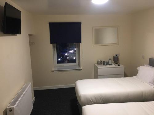 een hotelkamer met 2 bedden en een raam bij Stonefield Rooms in High Blantyre
