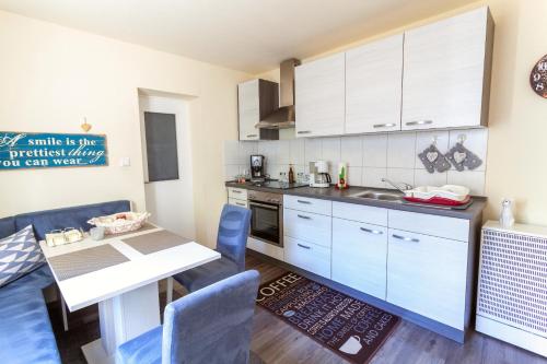 eine Küche mit weißen Schränken sowie einem Tisch und Stühlen in der Unterkunft Ferienwohnung Emmi in Bad Neuenahr-Ahrweiler