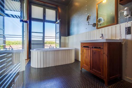 ein Badezimmer mit zwei Waschbecken, einer Badewanne und einem Fenster in der Unterkunft Hotel Dömitzer Hafen in Dömitz
