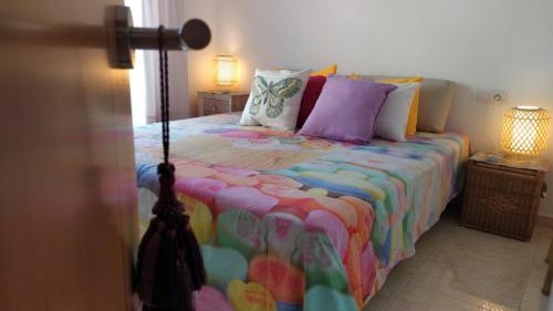 a bedroom with a bed with colorful sheets and pillows at Bara Blanc Beach in Roda de Bará
