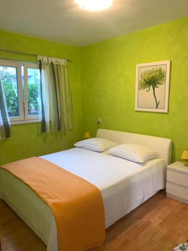 a bedroom with a large bed with green walls at Villa Perla Rogoznica in Rogoznica