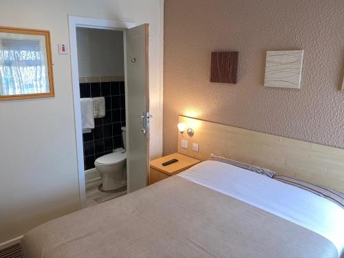 a bedroom with a bed and a bathroom with a toilet at Grange House Hotel in Blackpool