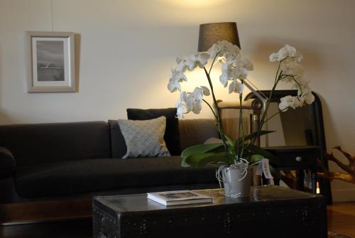 a living room with a couch and a table with white flowers at Appartement d'Hôtes Temps de Pause in Lautrec
