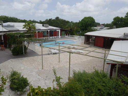 a large swimming pool with a tennis court in front of a building at Les Gîtes De L'union in Les Abymes