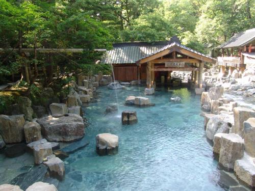 una piscina de agua azul con rocas y un edificio en Takaragawa Onsen Ousenkaku en Minakami
