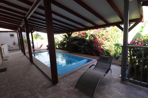 a patio with a swimming pool and a chair at Les Gîtes De L'union in Les Abymes