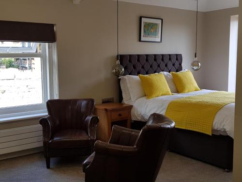 a bedroom with a bed and a chair and a window at The Bowes Hotel in Bardon Mill