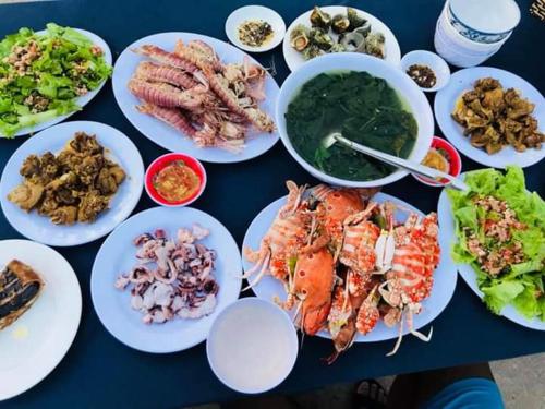 Chamisland Hanhly homestay في هوي ان: طاولة مليئة بأطباق الطعام مع المأكولات البحرية والخضروات