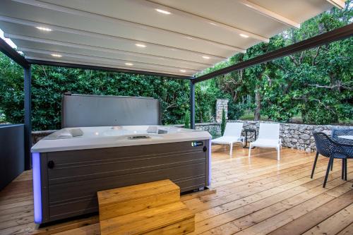 a large hot tub on a wooden deck with chairs at Happy Apartments Baška in Baška