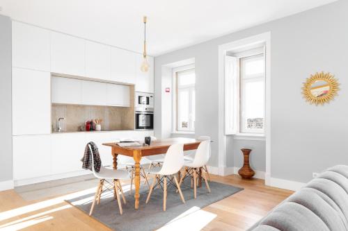 a kitchen and dining room with a wooden table and white chairs at ALTIDO Marvelous 3-bed home with astonishing view and terrace, nearby St George Castle in Lisbon