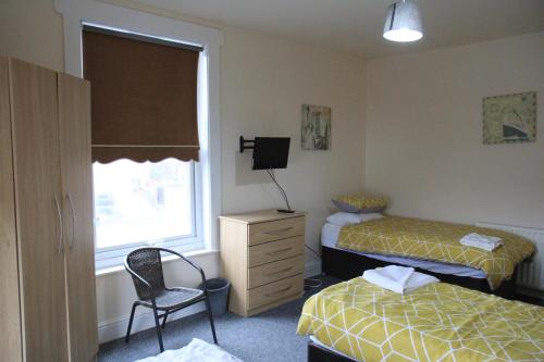 1 dormitorio con 2 camas, silla y ventana en Clifton arms, en Liverpool