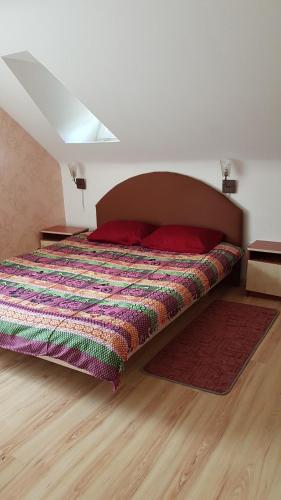 a bedroom with a bed with a colorful comforter at GRAŽINOS SODYBA in Telšiai