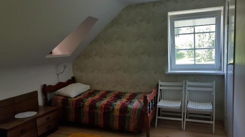 a bedroom with a bed and a window and two chairs at GRAŽINOS SODYBA in Telšiai