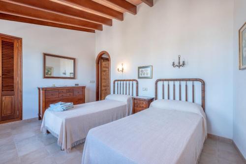 a bedroom with two beds and a dresser and a mirror at S'era in Santanyi