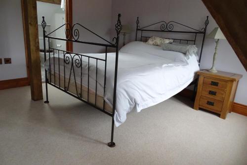 a bedroom with a black bed with white sheets at The Dairy at High House in Tintinhull