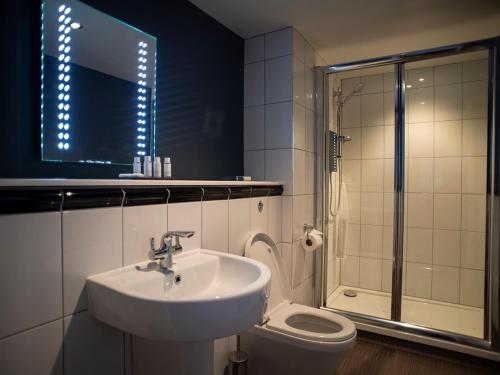 La salle de bains est pourvue d'un lavabo, d'une douche et de toilettes. dans l'établissement The Exeter Inn, à Bampton
