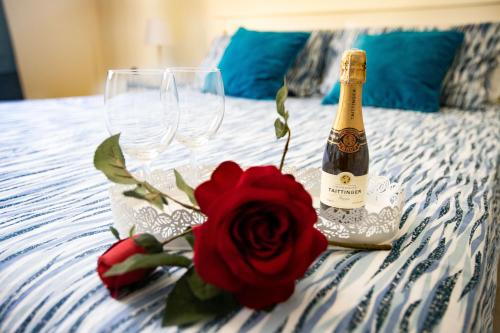 a bottle of champagne and a red rose on a bed at La casa di Nana’ locazione turistica in Palermo