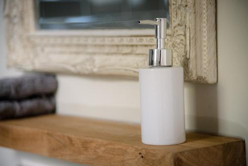 a white soap dispenser sitting on a wooden table at The Golden Key in Snape