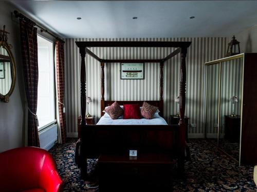 a bedroom with a canopy bed with red pillows at Pier 36 in Donaghadee