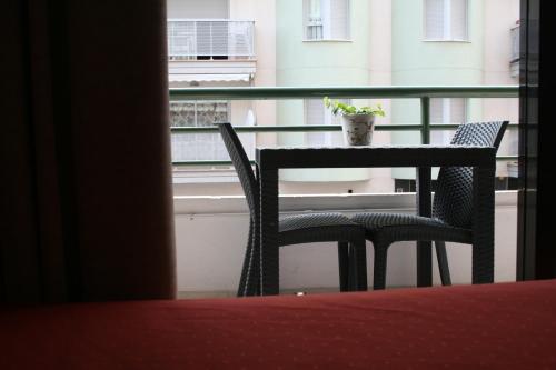 una mesa y sillas en un balcón con una maceta en Hostal Rosa, en Villajoyosa